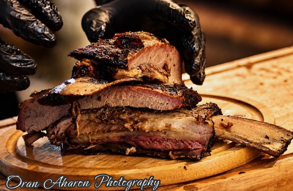 Close-up of smoked short ribs held in gloved hands
